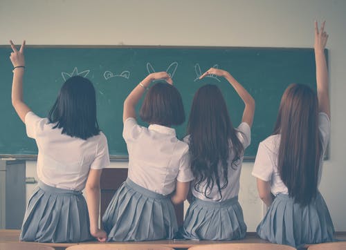 5 girls sitting on a desk in a classroom